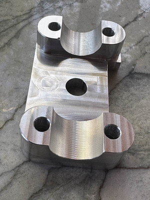 On the bottom side of the part, a subtle scalloping is visible on the U-shaped spaces where the handlebar tube goes