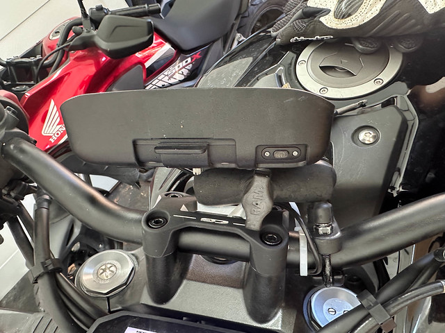A black plastic contraption is mounted on the handlebars of a motorcycle using RAM ball-and-socket joints