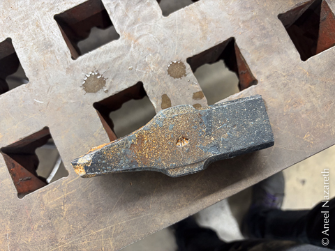 A side view of the hammer head showing the tapered cross peen and the square face. There's some vermiculite still stuck to it