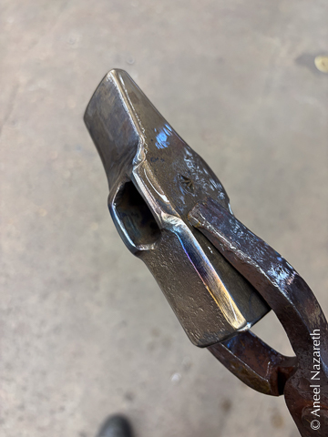 The hammer head is now smooth. It is mostly golden, but there's a bit of blue and purple near the eye