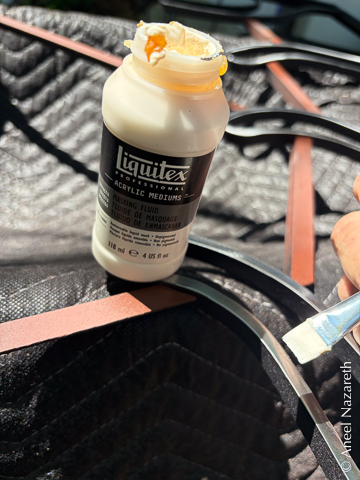 A brush is being used to apply liquid latex to the clearcoated tentacles, which are very shiny