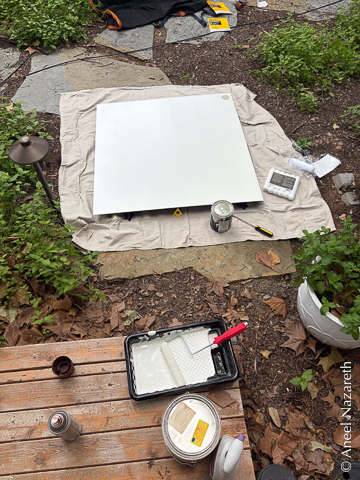 The inside panel of the door is on a drop cloth on the ground. There's a paint tray with a roller next to it.