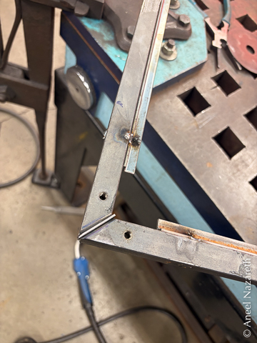 A corner of the frame is shown with a piece of 16 gauge steel in a gap between the two bars