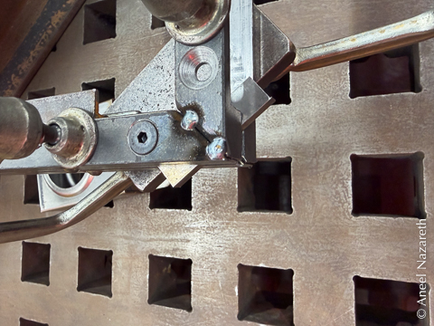 A corner of the frame is shown. It's clamped to a flat plate with two clamps. There are two tack welds at the corner