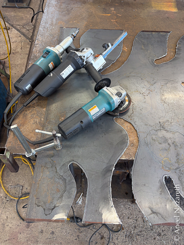 A die grinder, dynafile, and angle grinder on top of the sheet. You can still see dross from the plasma cutting and the marker line
