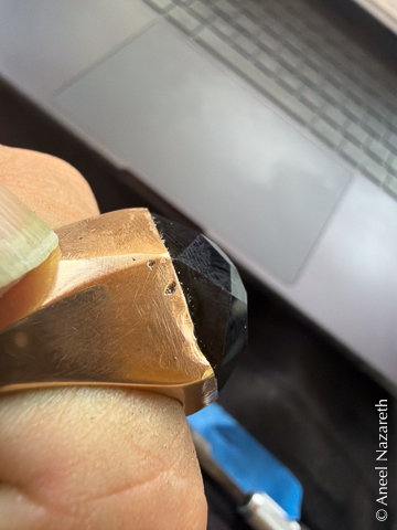 A closeup of one side of the ring, showing denting of the bezel and some spots of porosity