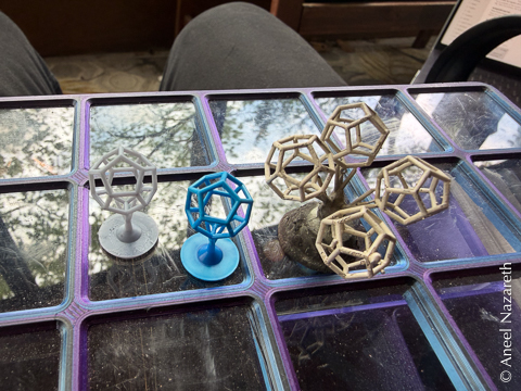 Resin printed dodecahedra next to a casting of a tree with four dodecahedra