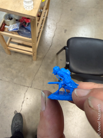 A miniature of a goblin with a sword in blue 3D printed wax resin